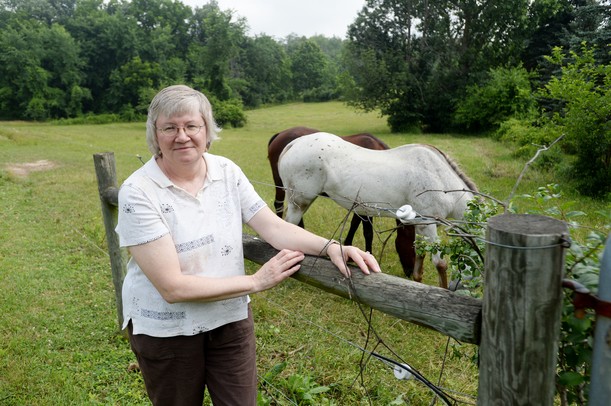 Lorie Armbruster poses for a photo with her horses at her Saline Township home. The Armbrusters have been struggling with the Paxton Resources over whether to give up their mineral rights in a lease with the company, or be forced to give them up in a state hearing. Melanie Maxwell | AnnArbor.com
